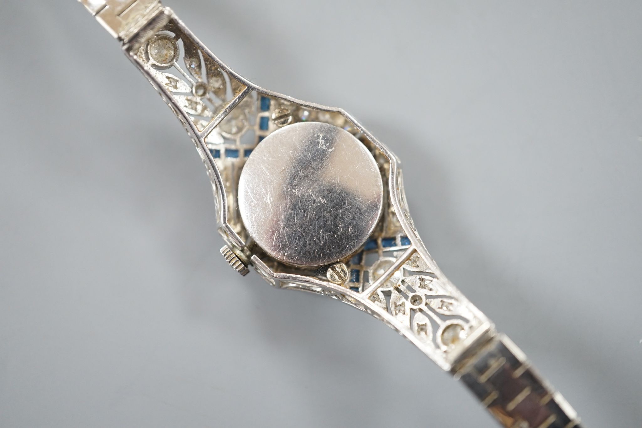 A mid 20th century white metal, synthetic sapphire? and diamond set cocktail watch, with Bucherer manual wind movement and dial bearing the signature Cartier, on a 14k white metal bracelet, case diameter 22mm, gross weig